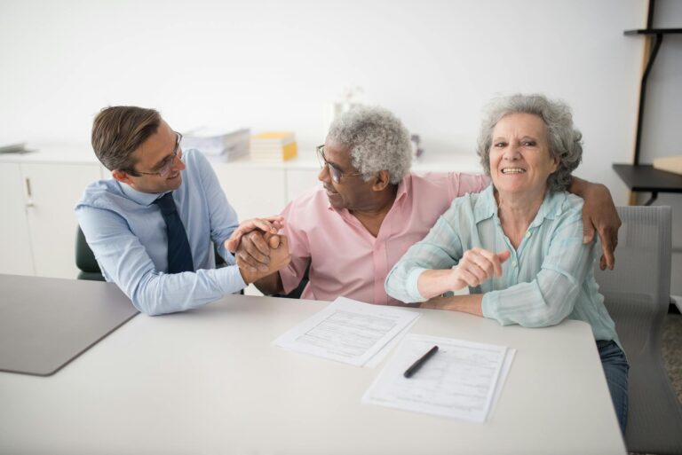 Senior couple in office meeting with consultant, discussing financial documents and smiling.